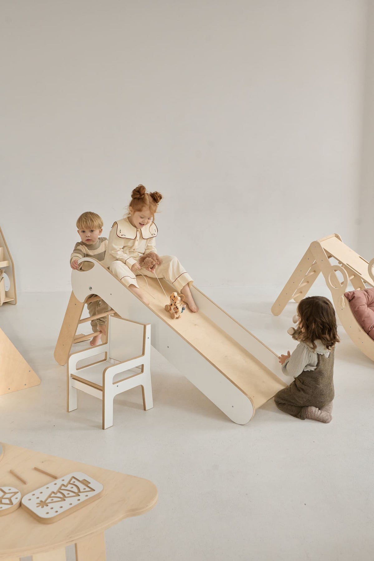 Kind rutscht auf der klappbaren Kinderrutsche aus Holz