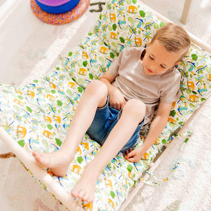 Glückliches Kind sitzt auf einem bunten Kletterbogen mit tierischem Muster, ideal für Spielerlebnis und Komfort.