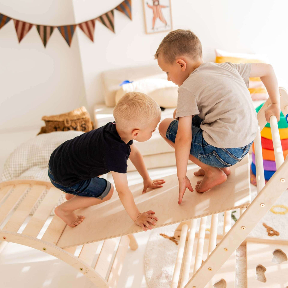 Zwei Kinder klettern spielerisch auf dem Kletterdreieck des Klettersets Äffchen aus Holz.