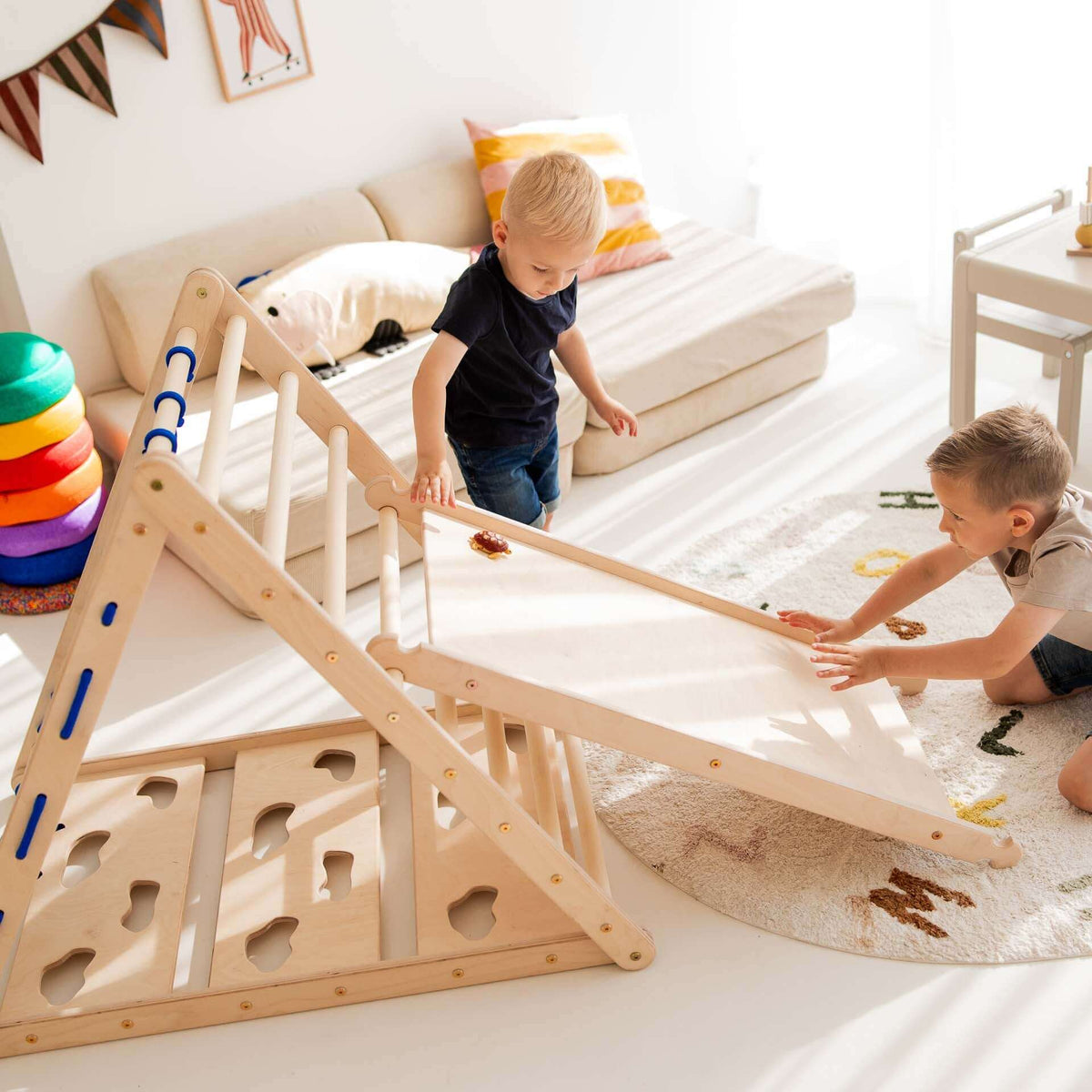 Zwei Kinder spielen mit dem Kletterset Löwe aus Holz, bestehend aus Kletterdreieck und Rutsche im hellen Raum.