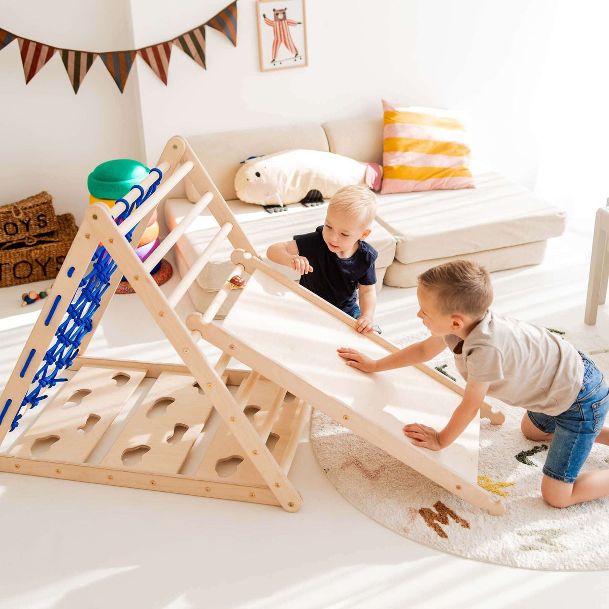 Zwei Kinder spielen mit einem Rutschbrett / Hühnerleiter, das mit einem Kletterdreieck kombiniert ist.