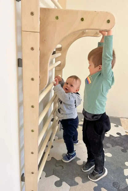 Zwei Kinder spielen an einer Kletterwand aus Holz und fördern ihre Kletterfähigkeiten und Beweglichkeit