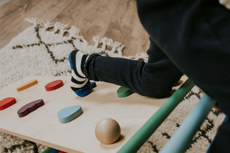 Kind klettert am Pikler Kletterdreieck mit Rampe und trainiert Gleichgewicht