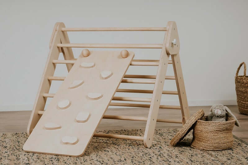 Kind klettert die Boulderwand-Seite der Rampe am Pikler Kletterdreieck hoch
