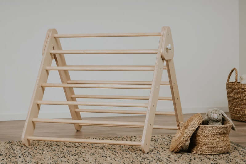 Kleinkind klettert am Pikler Kletterdreieck aus Holz im Kinderzimmer