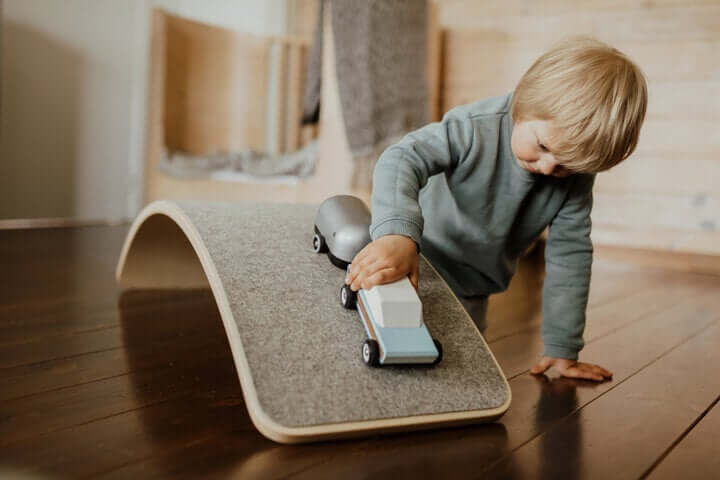 Kind balanciert auf dem Balance Board aus Holz